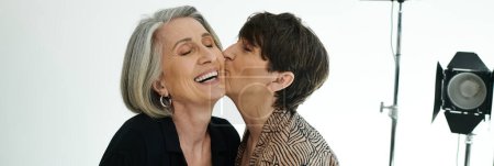 A middle-aged lesbian couple sharing a tender kiss in a photo studio