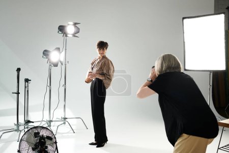 A middle-aged woman snaps a picture of her partner in a photo studio, capturing a moment of love and connection.