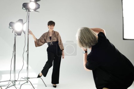 A middle-aged woman poses in a burst of light with a camera-wielding photographer, showcasing the art of photography.