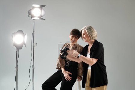 Ein lesbisches Paar mittleren Alters in einem Fotostudio, eine hält eine Kamera, während die andere lächelt