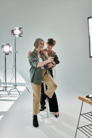 Ein lesbisches Paar mittleren Alters in einem Studio; überprüft Fotos vor der Kamera