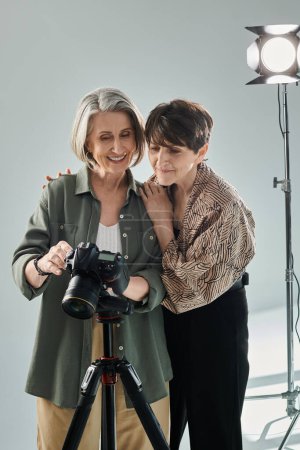 Zwei Frauen mittleren Alters, eine Fotografin hält eine Kamera in der Nähe eines Modells