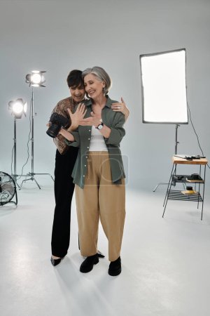 Couple lesbien d'âge moyen dans un studio, un avec caméra montrant des photos