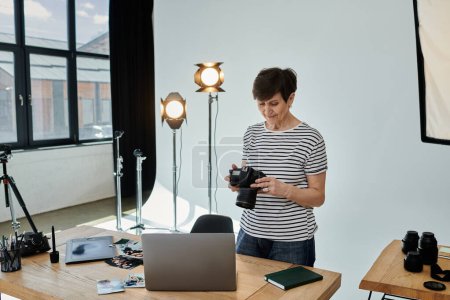 A woman skillfully holds a camera in front of a laptop screen, capturing digital content for creative purposes.