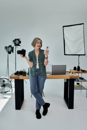 Frau mittleren Alters mit Kamera vor einem Schreibtisch in einem modernen Studio.