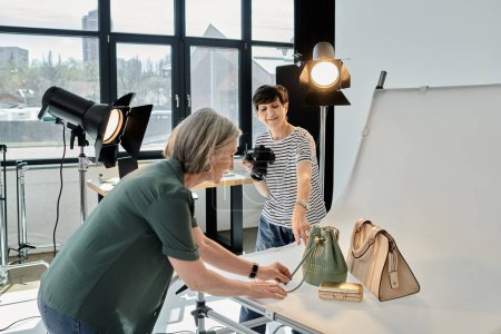 Ehepaar mittleren Alters arbeitet in professionellem Fotostudio, während eine Frau Taschen fotografiert