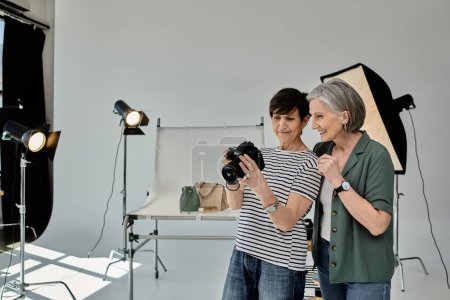 A woman in a photo studio takes a picture while using a camera, in a collaborative and creative setting.