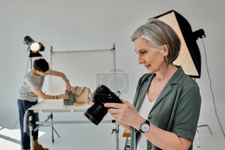 A middle-aged woman holds a camera in a modern photo studio setting.