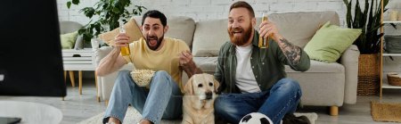 A gay couple and their Labrador sitting on top of a couch, watching a sports match in the living room.