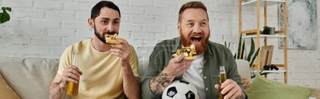 Foto de Two men with beards relax on a couch, eating pizza, drinking beer - Imagen libre de derechos