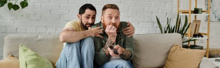 A couple of bearded men enjoy a relaxing moment while seated atop a comfortable couch in their living room.