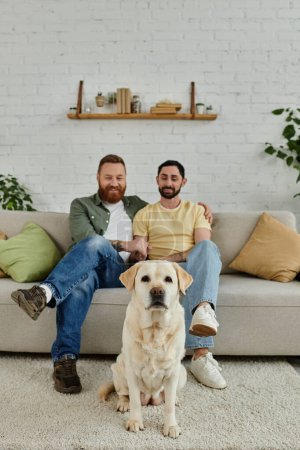 Zwei Männer mit Bärten verbringen ihre Zeit auf einer Couch mit ihrem schwarzen Labrador in einer gemütlichen Wohnzimmeratmosphäre.