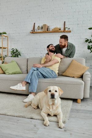 A bearded gay couple enjoys quality time together with their Labrador on a comfortable couch in their living room.
