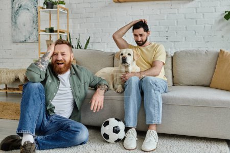 Im Wohnzimmer sitzt ein Mann mit seinem Labrador-Hund auf einer Couch und schaut sich gemeinsam ein Sportspiel an.