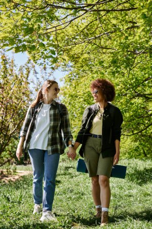 A young lesbian couple walks hand-in-hand through a forest, enjoying the outdoors.