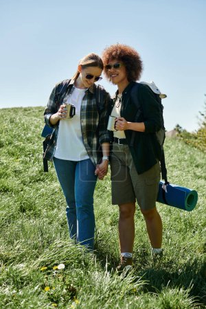 A lesbian couple hikes together in the wilderness, enjoying the scenery and each others company.