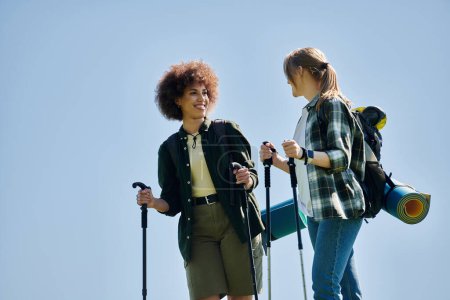 Zwei junge Frauen, ein lesbisches Paar, wandern gemeinsam in der Wildnis und genießen ein landschaftliches Outdoor-Abenteuer.