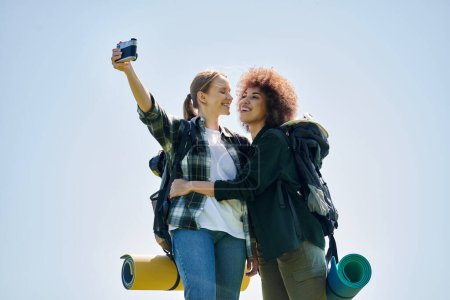 Two young women take a selfie while hiking in the wilderness, embracing the outdoors.