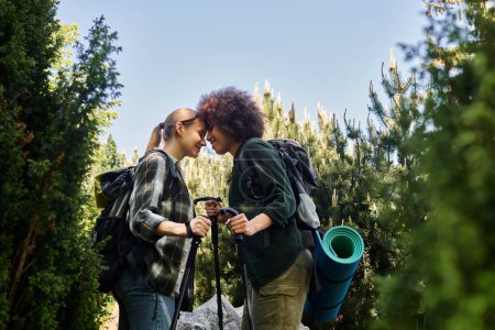 Zwei junge Frauen, ein lesbisches Paar, wandern durch ein Waldgebiet und genießen gemeinsam die Natur.