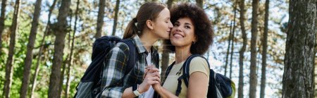 A young lesbian couple shares a tender moment during a hike through a wooded area.