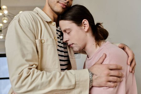 Foto de Una joven pareja gay se abraza en un apartamento moderno, mostrando un tierno momento de intimidad y afecto. - Imagen libre de derechos
