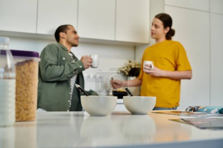 Two young men are enjoying coffee together in a modern apartment.