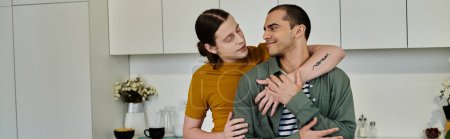 A young gay couple shares a tender moment of affection in their modern apartment kitchen.