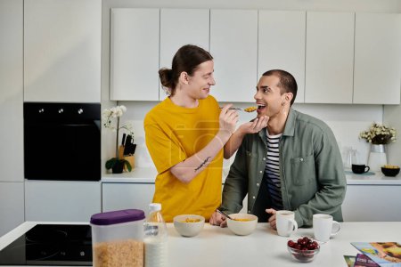A young gay couple shares a lighthearted moment in their modern apartment kitchen, enjoying breakfast together.