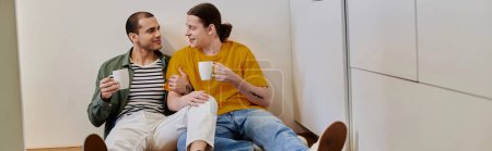 A young gay couple shares a tender moment in their modern apartment, enjoying a drink together.