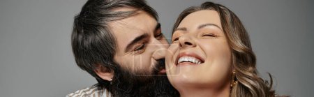Una pareja con un atuendo elegante comparte un momento tierno, la mujer riendo mientras su pareja se inclina para un beso.