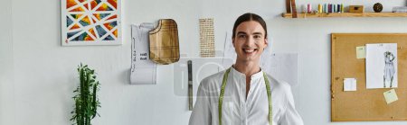 Un joven sonríe con confianza en su taller de restauración de ropa, rodeado de herramientas de su oficio y una pasión por la sostenibilidad.