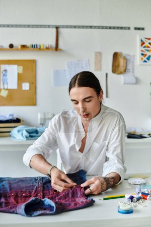 Photo for A young man meticulously repairs a vintage denim shirt in his sustainable clothing restoration atelier. - Royalty Free Image