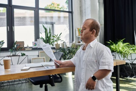 Ein Mann mit weißem Hemd steht an einem Schreibtisch in einem modernen Büro und überprüft ein Dokument.