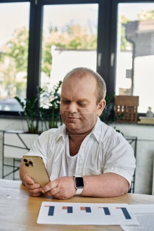 Un hombre con inclusividad trabaja en un escritorio en un entorno de oficina, usando un teléfono inteligente.