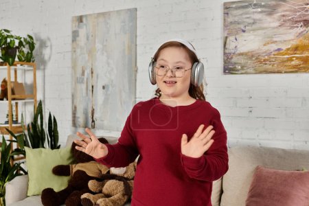 A little girl with Down syndrome dances to music while wearing headphones at home.