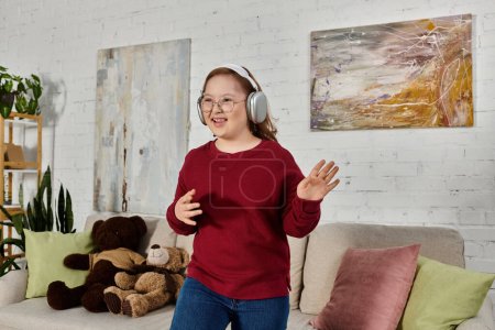 A little girl with Down syndrome wearing headphones dances in her home.