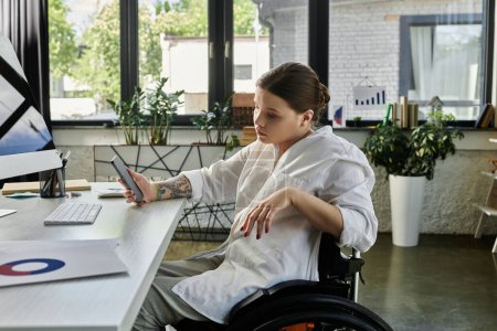 Eine junge Geschäftsfrau im Rollstuhl arbeitet in einem modernen Büro an ihrem Computer.
