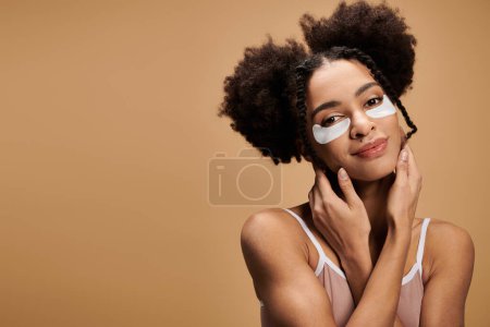 Una hermosa joven afroamericana con parches en los ojos sonríe suavemente sobre un fondo beige.