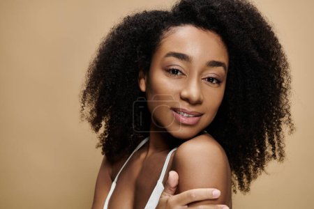 Téléchargez les photos : Portrait en gros plan d'une belle Afro-Américaine au maquillage naturel, souriant doucement. - en image libre de droit