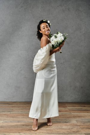 A beautiful African American bride in a white wedding dress with flowers in her hair, smiling and holding a bouquet.
