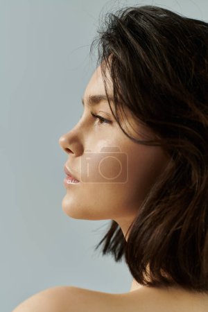 Illuminated by soft light, a woman with short, dark hair gazes into the distance.