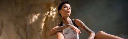 Téléchargez les photos : Vue du bas de l'archéologue sexy avec tatouage et cheveux courts, bannière - en image libre de droit