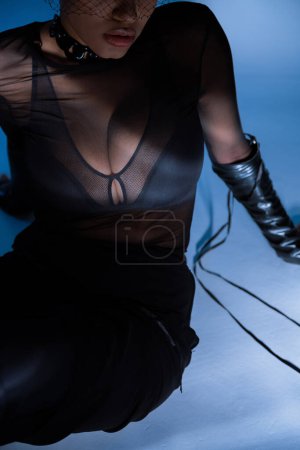cropped view of african american woman in transparent shirt and black bra posing on blue 
