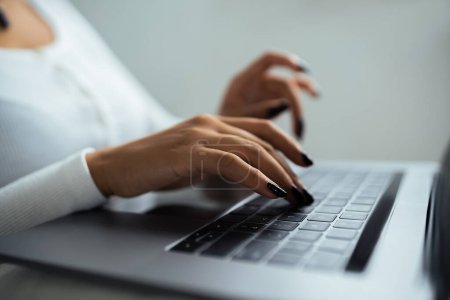 Téléchargez les photos : Vue recadrée de la jeune femme afro-américaine tapant sur le clavier de l'ordinateur portable - en image libre de droit