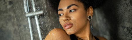 Hübsche afrikanisch-amerikanische Frau steht unter Wasser, während sie duscht, Banner 