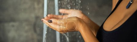 Cropped view of african american woman holding hands under water in shower, banner 