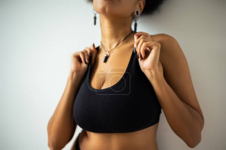 Cropped view of blurred african american woman touching black crop top near wall 