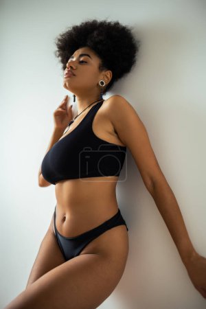 Sexy femme afro-américaine en sous-vêtements noirs debout près du mur 
