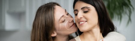 Lesbian woman hugging and kissing partner at home, banner 