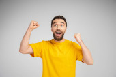 excited bearded man in yellow t-shirt screaming and showing success gesture isolated on grey t-shirt #621214736
